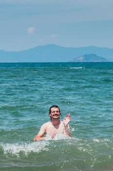 Handsome man having fun in the sea, splashing water. Summer holiday concept photo