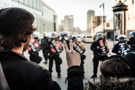 MONTREAL, CANADA APRIL 02 2015 - Man making a Peace sign in front of cops photo