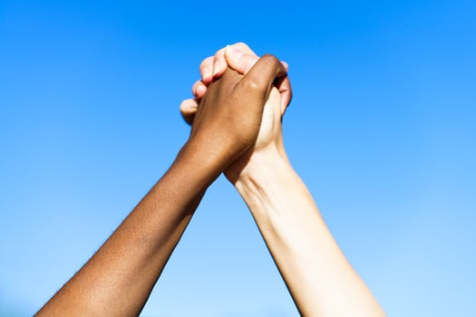 Multiethnic women's hands together against blue sky. photo