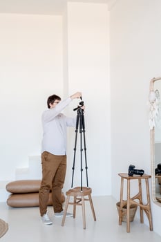 Male photographer working in minimal light and airy interior , white and beige chair, rug and pillows photo