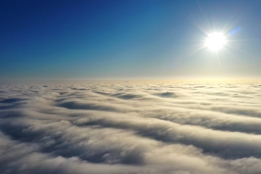 Aerial photography, bright sun above the horizon and above dense gray clouds in a dark blue sky. photo