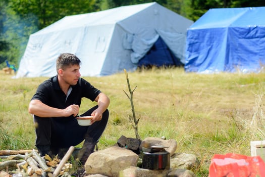 A man dishes while traveling in the nature on the background of tents photo