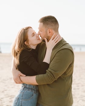 Young adult couple standing on beach and looking each other. photo