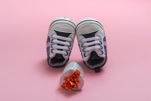 Mockup of children's shoes. Close up of a gift box and gumshoes for a newborn on a colored background. A gift to father photo