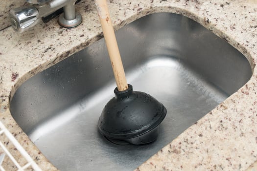 Man Using a Plunger to unstop his kitchen sink photo