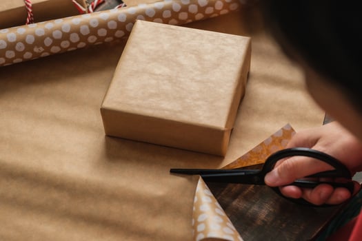 Close up woman hand cutting kraft paper to wrapping christmas gift box on wood table photo