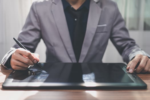 A man in a suit is writing on a tablet photo