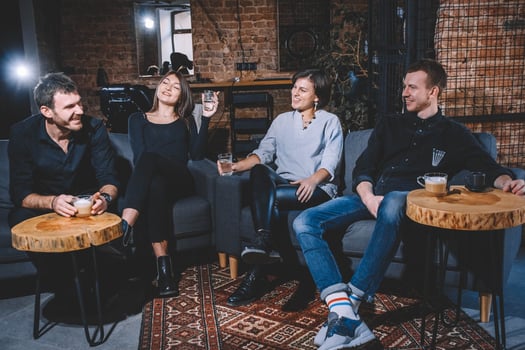 Cheerful guys and girls are sitting on sofa with cups in hands photo