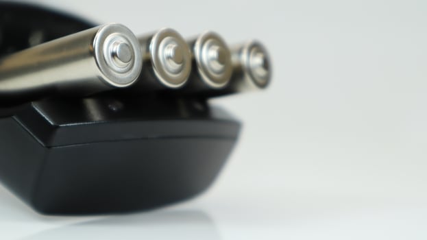 Rechargeable alkaline batteries in a battery charger on a white background. AA fast charger in black. The battery is charging. photo