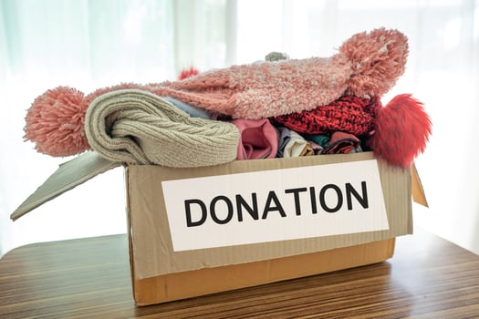 Holding clothing donation box with used clothes and doll at home to support help for poor people in the world. photo