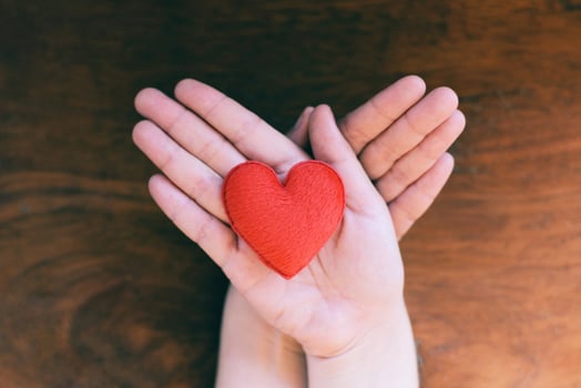 heart in hand for philanthropy concept - woman holding red heart on hands for valentines day or donate help give love warmth take care with wooden background photo