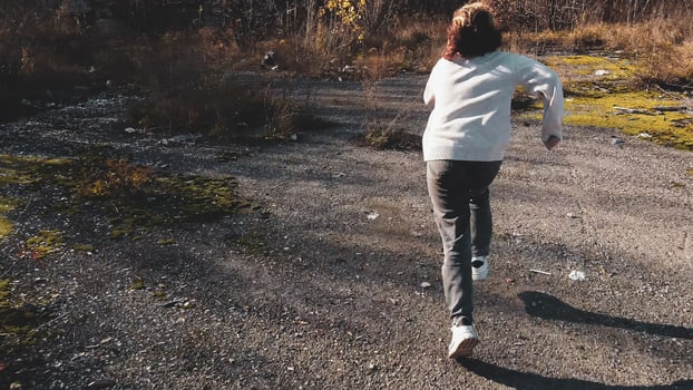 a teenage girl quickly runs away from a maniac on a rural road near a landfill photo