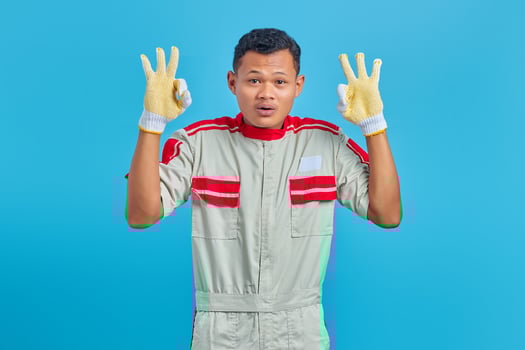 Cheerful young Asian mechanic making okay gesture, showing approval symbol isolated on blue background photo