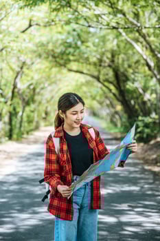 Female tourists stand and look at the map on the road. photo