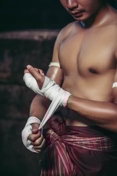 The boxer sat on the stone, tied the tape around his hand, preparing to fight. photo