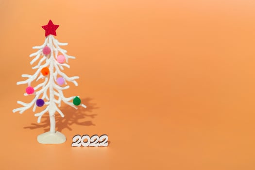 Christmas card. Against the background of Christmas lights, a white Christmas tree in multi-colored fur toys with the numbers 2022. copy space photo