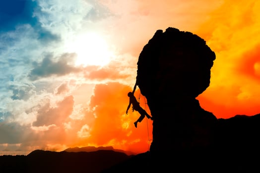 lone climber almost at the top of the mountain at sunset with a photo