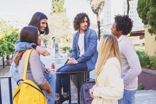 Multi-ethnic group of friends gathered in the street leaning on a railing. photo