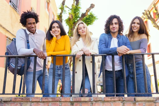 Multi-ethnic group of friends gathered in the street leaning on a railing. photo