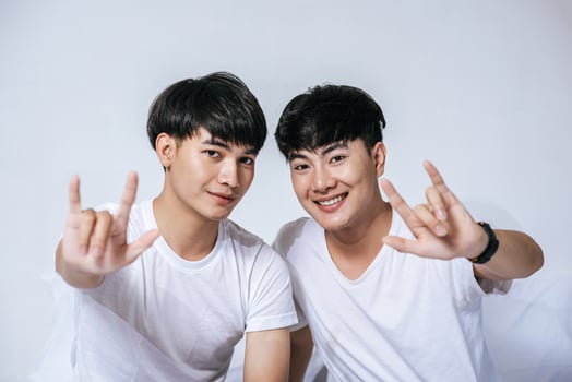 Two loving young men look at each other and make a hand of love symbol. photo