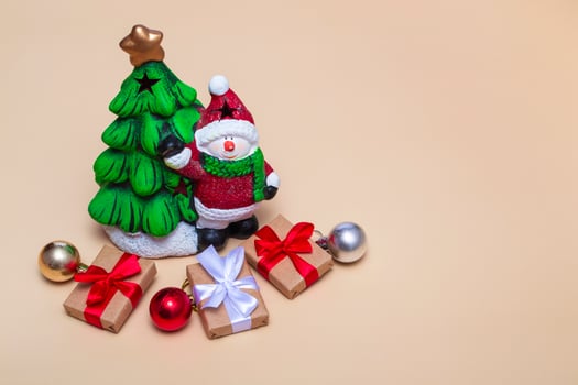 Christmas card. New Year tree with a snowman and gifts on a beige background. Close up, copy space photo