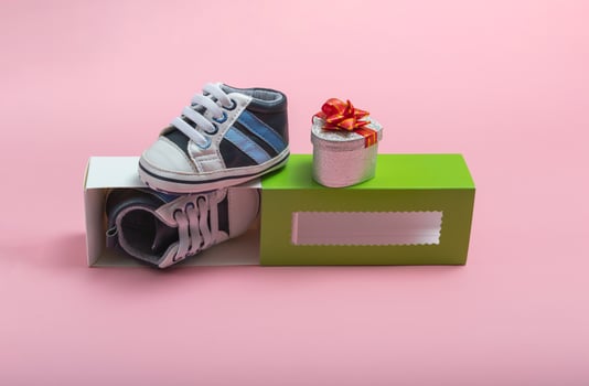 Mockup of children's shoes. Close up of a gift box and gumshoes for a newborn on a colored background. A gift to father photo