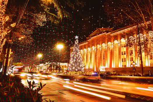 Cars in traffic on rush hours at night in rustaveli avenue in capital city Tbilisi in Georgia on xmas with xmas tree by parliament on background photo