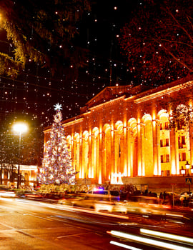 Cars on road in traffic on rush hours at night in rustaveli avenue in capital city Tbilisi in Georgia on Christmas with xmas tree by parliament on background photo