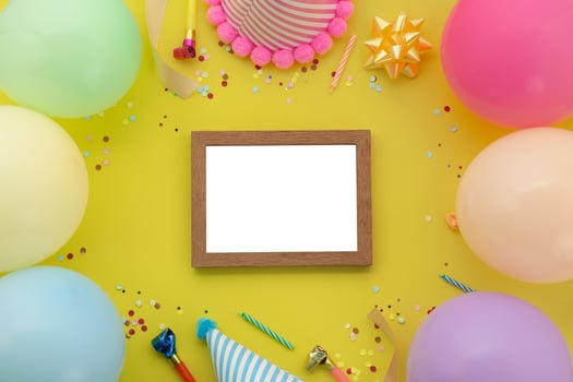 Happy birthday background, Flat lay colorful party decoration with photo frame on pastel yellow background
