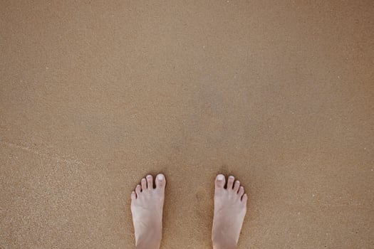 Summer vacation concept barefoot on sand at beach with copyspace. photo