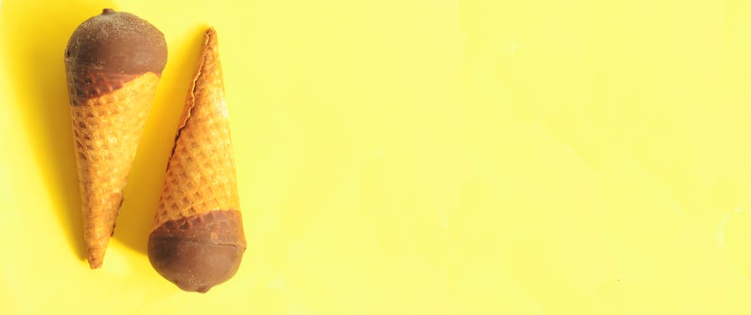 Two sunny chocolate ice-cream cones on yellow background, copyspace. photo