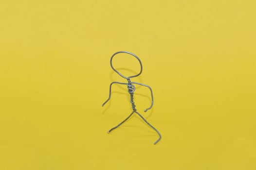 Metal man made of wire stands on yellow background photo