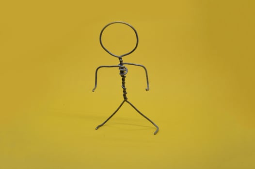 Metal man made of wire stands on yellow background photo