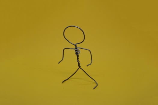 Metal man made of wire stands on yellow background photo