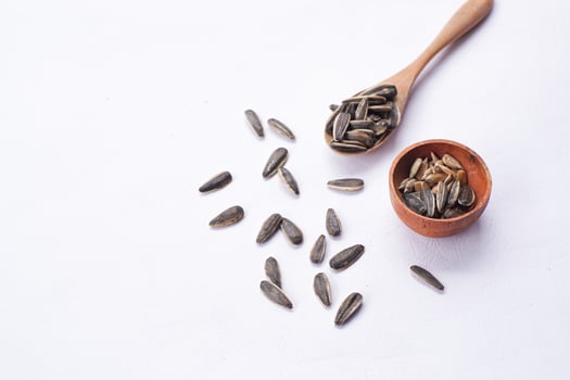 Sunflower seeds in a wooden bowl on a white table photo