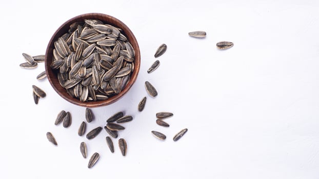 Sunflower seeds in a wooden bowl on a white table photo
