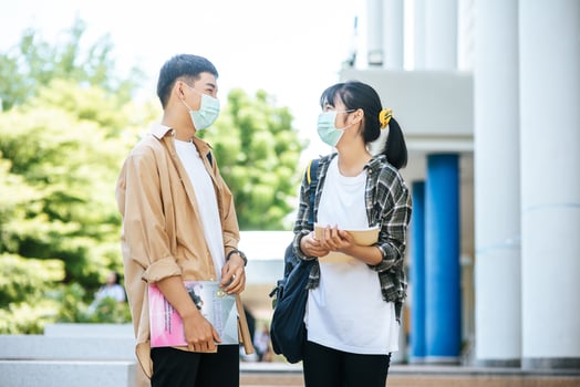 Male and female students wear a health mask and talk to each other on the stairs. photo
