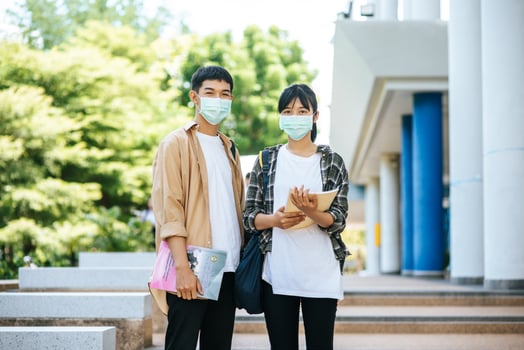Male and female students wear a health mask and talk to each other on the stairs. photo
