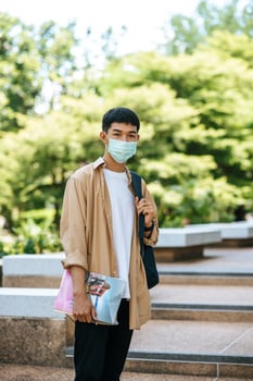 Men wear masks, carry books, and carry a backpack on the stairs. photo
