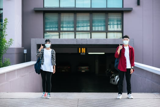 Male and female students wear masks and stand in front of the university. photo