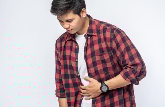 A man stands with a stomachache and puts his hand on his stomach. photo