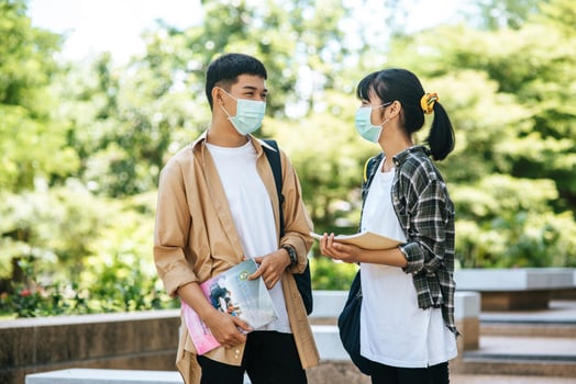 Male and female students wear a health mask and talk to each other on the stairs. photo
