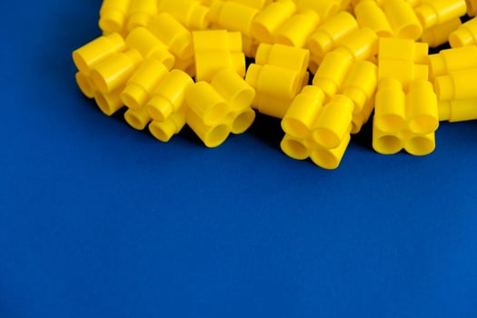 Yellow plastic building blocks on a blue background photo