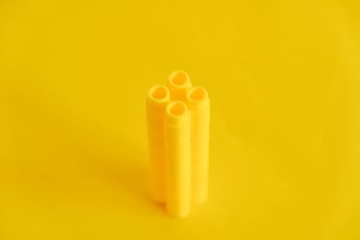 Yellow plastic building blocks in shape of a tower on yellow background photo