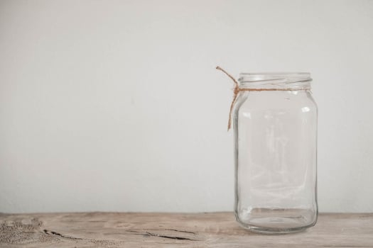 Glass transparent jar on wooden table on white wall background photo
