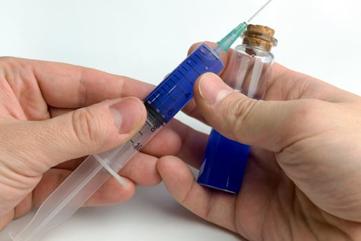 Hand holding test tube with blue liquid and a syringe. photo