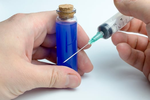 Hand holding test tube with blue liquid and a syringe. photo
