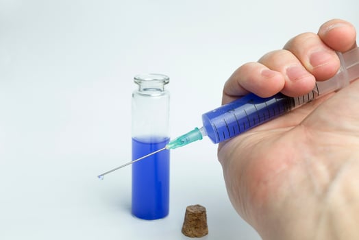 Hand holding test tube with blue liquid and a syringe. photo