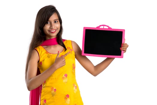 Beautiful young girl holding and showing something on a chalkboard or slate, isolated over white background photo