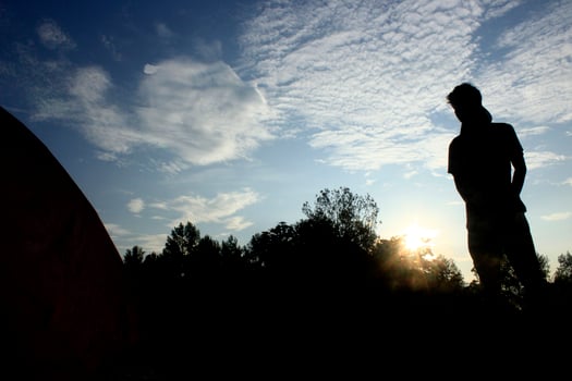 silhouette of a climber with a tent on bright blue sky background photo